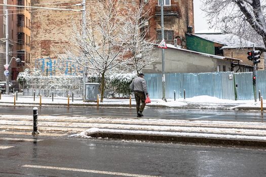 Pedestrian crossing the snowy road, snowy winter day in Bucharest, Romania, 2021