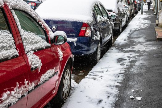 Snow on cars in the morning. Winter season, icy cars. Winter concept, frozen cars on the road in Bucharest, Romania, 2021