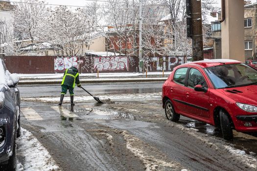 Snow removal, worker cleaning the snowy road in Bucharest, Romania, 2021