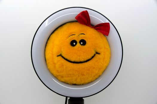 Smiley yellow soft toy with a red bow in a ring lamp.