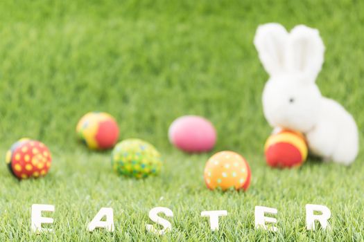 Easter bunny toy and Easter eggs with text on green grass