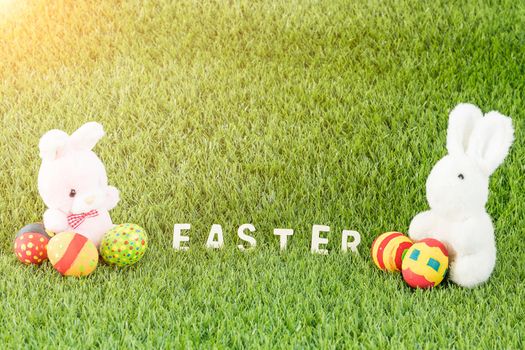 Easter bunny toy and Easter eggs on green grass with text