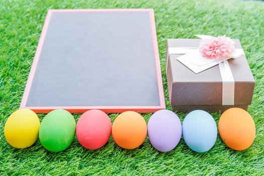 Close up Colorful easter eggs on green grass and blackboard mockup with copy space