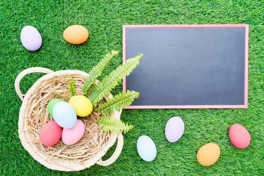 Close up Colorful easter eggs on green grass and blackboard mockup with copy space