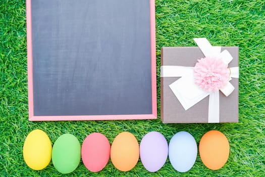 Close up Colorful easter eggs on green grass and blackboard mockup with copy space