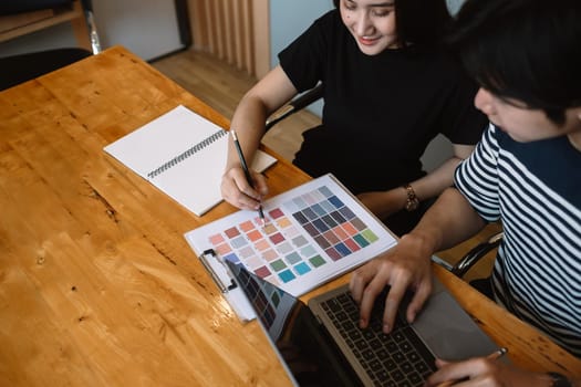 Group of young designers in casual clothes is using a laptop, discussing affairs