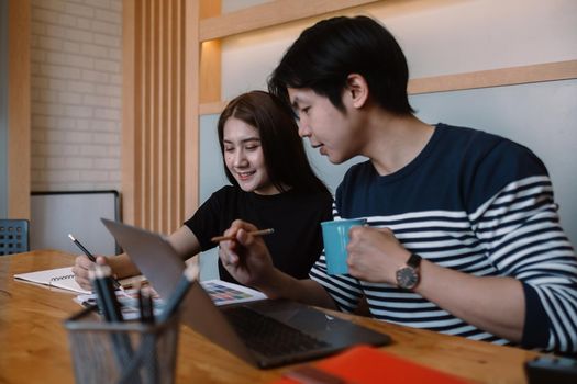 Group of young designers in casual clothes is using a laptop, discussing affairs