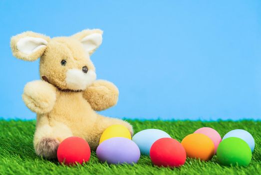 Colorful easter eggs and bunny on grass with blue background