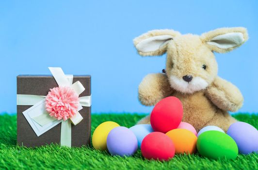 Colorful Easter eggs and gift box on grass  with blue background