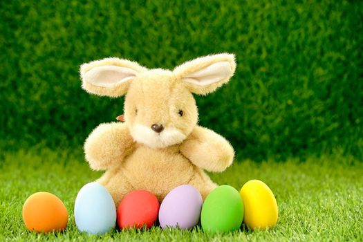 Colorful easter eggs and bunny on grass with blue background