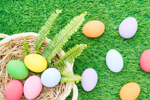 Colorful easter eggs in the basket on grass background with copy space