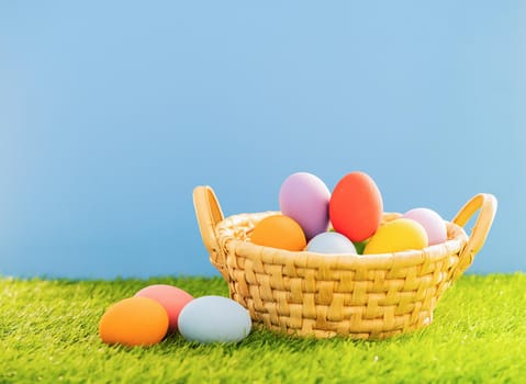 Colorful easter eggs in the basket on green grass background with copy space