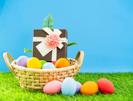 Colorful easter eggs in the basket on green grass background with copy space