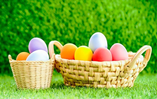 Colorful easter eggs in the basket on green grass background with copy space