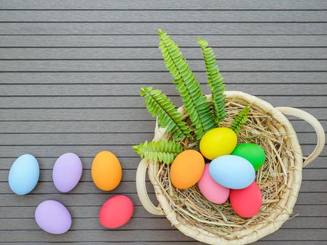 Colorful easter eggs in the basket on wood background with space