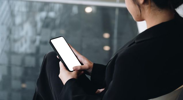 Businesswoman holding smart phone with white blank screen. For Graphic display montage.