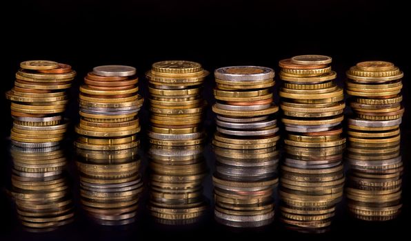 Stacks cf different country coins on black background.