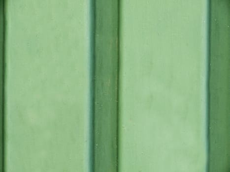 Green smooth concrete wall with striped vertical stripes close-up.Texture or background