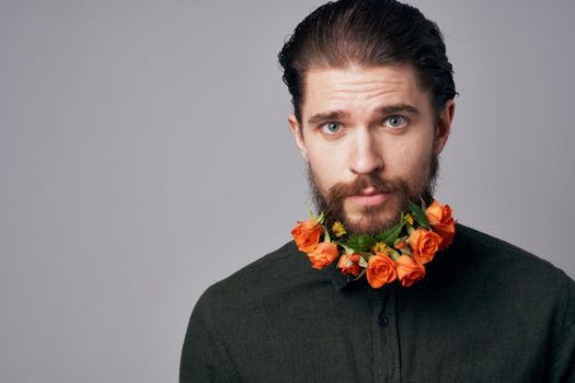 Cute elegant man in a black shirt flowers in a beard decoration romance gray background. High quality photo