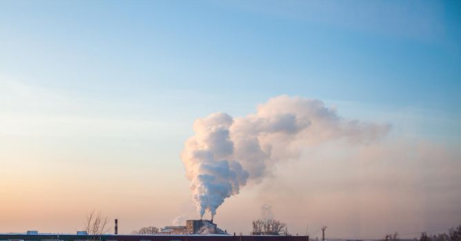 White thick smoke from the boiler room chimney. Smoke against the blue sky. Air pollution. Heating of the city. Industrial zone.