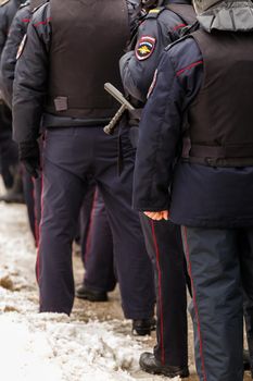 Tula, Russia - January 23, 2021: Crowd of police officers in black uniform with bulletproof vests and pistols - view from back. Close-up.