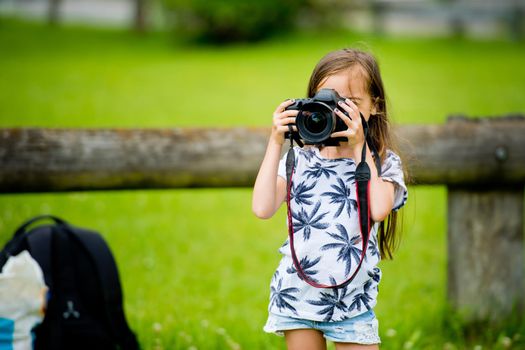 A cute little brunette girl is holding a camera.