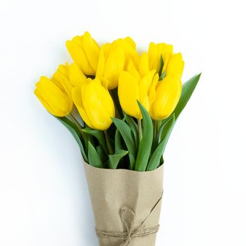 Bouquet of yellow tulips wrapped in craft paper on a white background.