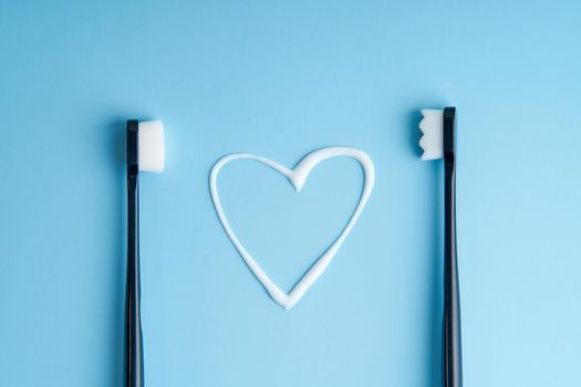 Heart shaped toothpaste between two toothbrushes.