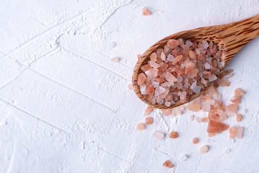 Pink Himalayan salt on a wooden spoon isolated on white background
