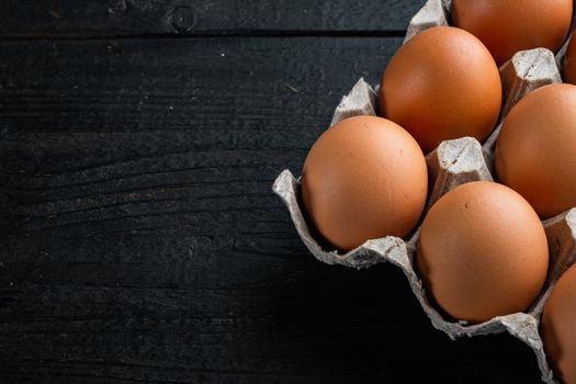 Fresh eggs on paper egg box set, on black wooden table background , with space for text copyspace