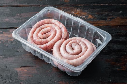 Raw snail sausage in traditional spiral set, on old dark wooden table background, in plastic pack