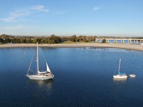 Aerial view of small sail boats in the Mission Bay of San Diego, California, USA. Small sailing ship yachts anchored in the bay. March 22nd, 2020