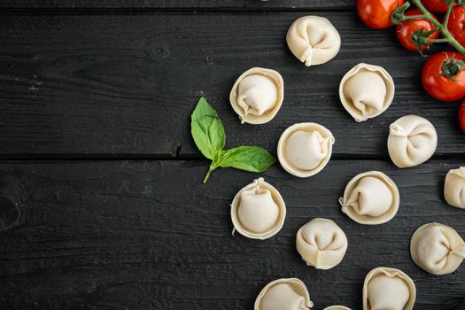 Italian tortellini with fresh ricotta leaves and tomatoes set, on black wooden table background, top view flat lay , with copyspace and space for text