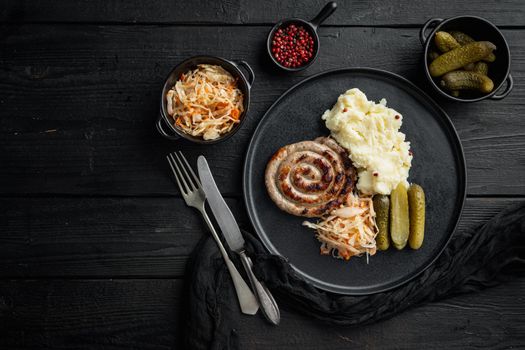 Bavarian sausage mashed potatoe and sour cabbage, on black wooden table background, top view flat lay , with space for text copyspace