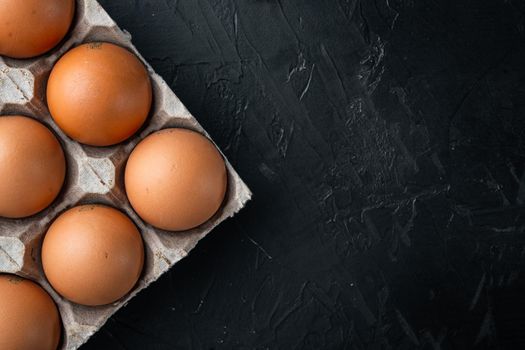 Brown eggs in carton box tray set, on black background, top view flat lay , with space for text copyspace
