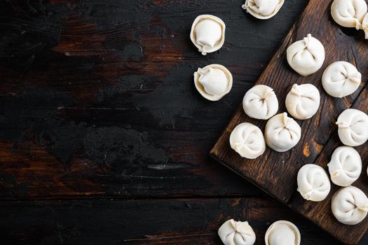 Frozen dumplings tortellini and ravioli set on cutting board on old dark wooden table background, top view flat lay , with copyspace and space for text