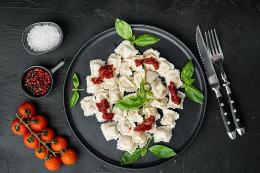 Ravioli pasta with mushroom cream sauce and cheese - Italian food style set with basil parmesan and tomatoe on black plate, on black background, top view flat lay
