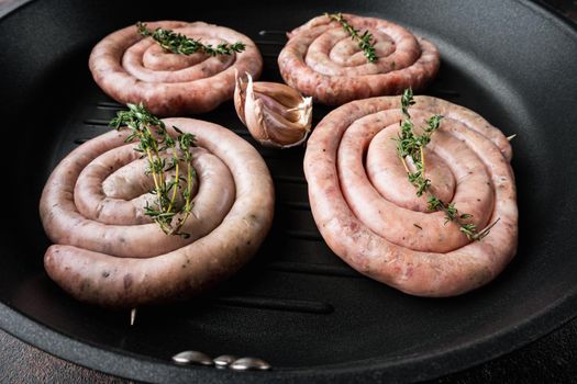 Raw spiral sausage set in cast iron frying pan, on old dark rustic background