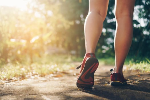 Woman wear running shoe on to walking and running on nature green background.Health exercise concept.