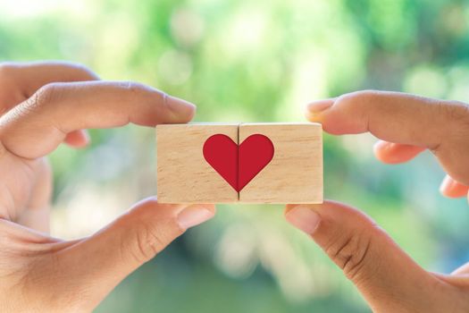 Hand hold wooden cube with heart sign icon on and copy space nature sunlight you can put text on background. Valentine love season concept.