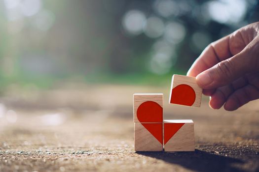 Hand hold wooden cube with heart sign icon on and copy space nature sunlight you can put text on background. Valentine love season concept.