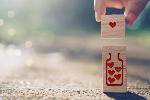 Hand hold wooden cube with heart sign icon on and copy space nature sunlight you can put text on background. Valentine love season concept.