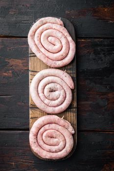 Traditional raw spiral pork sausages set, on old dark wooden table background, top view flat lay