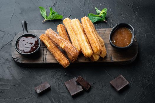 Traditional churros sticks with cinnamon and sugar powder set, on black background
