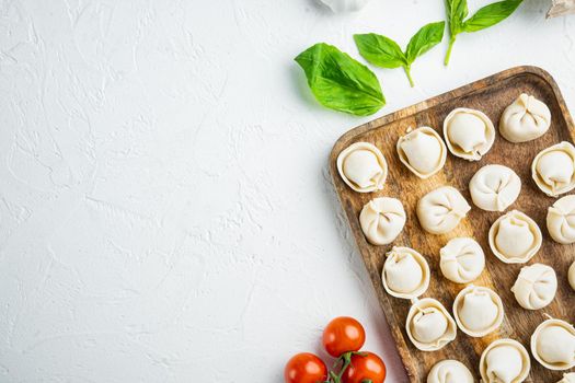 Italian tortellini with fresh ricotta leaves and tomatoes set in wooden tray, on white background, top view flat lay , with copyspace and space for text
