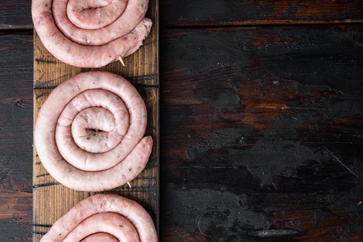Raw snail sausage in traditional spiral set, on old dark wooden table background, top view flat lay , with space for text copyspace