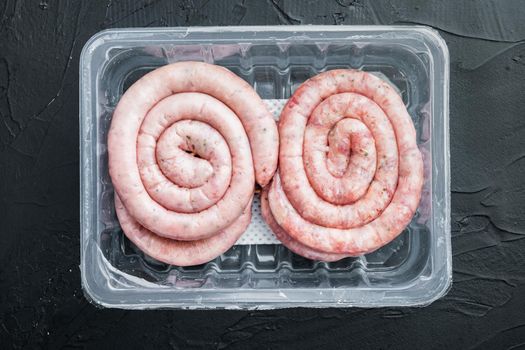 Raw meat sausage set, on black background, in plastic pack, top view flat lay