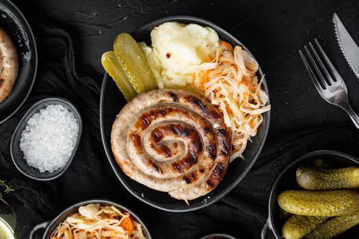 Roasted sausages with fermented cabbages, on black background, top view flat lay