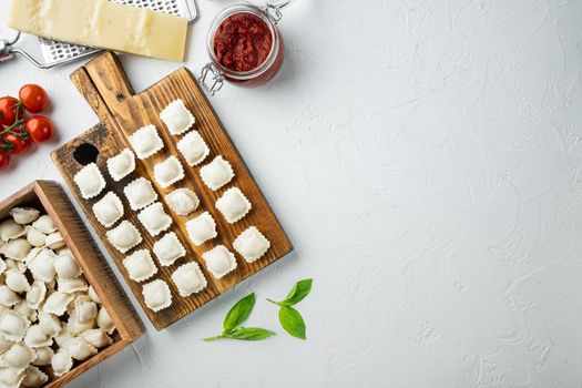 Raw Italian ravioli tortellini with fresh parmesan and basil , tomatoes set on wooden board, on white background, top view flat lay , with copyspace and space for text