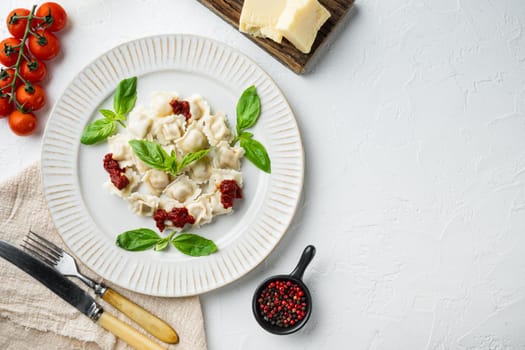 Appetizing ravioli with tomato sauce, cheese and basil set with basil parmesan and tomatoe on white plate, on white background, top view flat lay , with copyspace and space for text